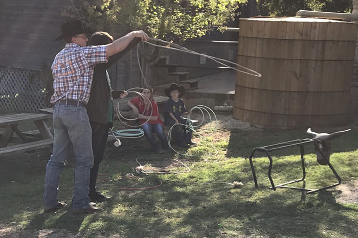 Man teaching youth how to lasso