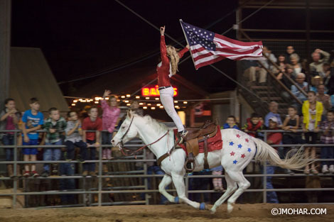 Rider standing on horse holding a US flag